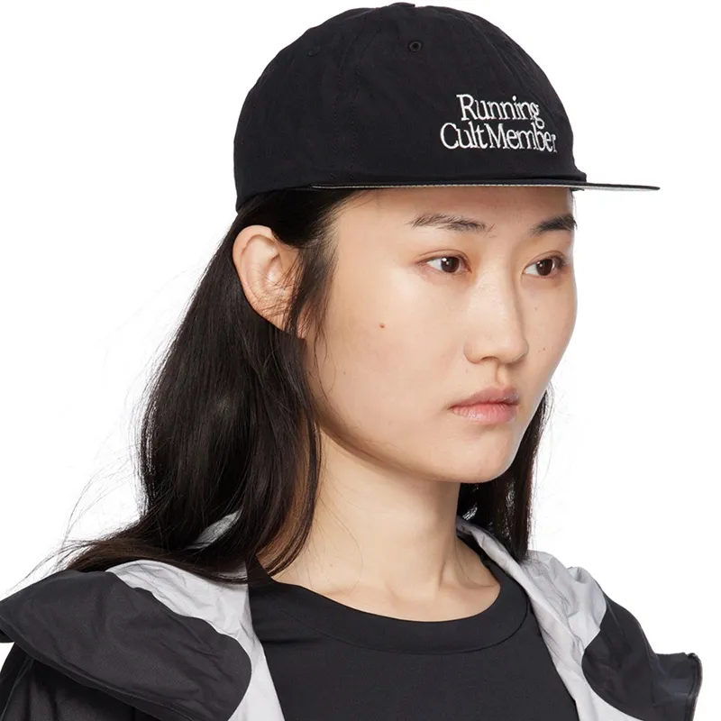 ผู้หญิงสวมหมวกวิ่งสีดำจาก SATISFY พร้อมโลโก้ Running Cult Member ในลุค activewear มินิมอล